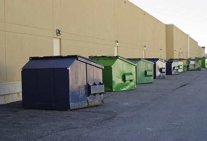 a pile of demolition waste sits beside a dumpster in a parking lot in Albion